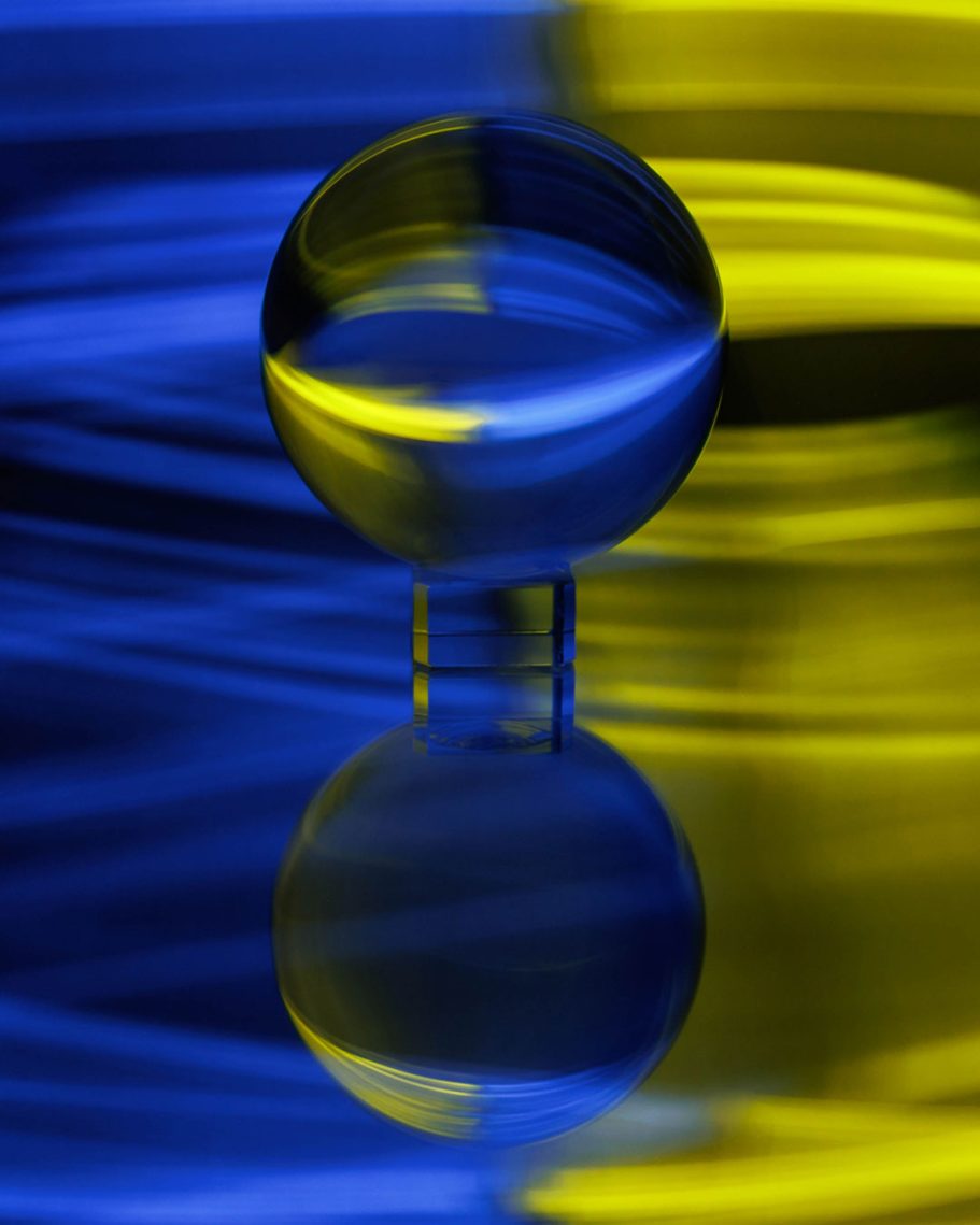 Eine transparente Kugel reflektiert blaue und gelbe Wellenmuster.