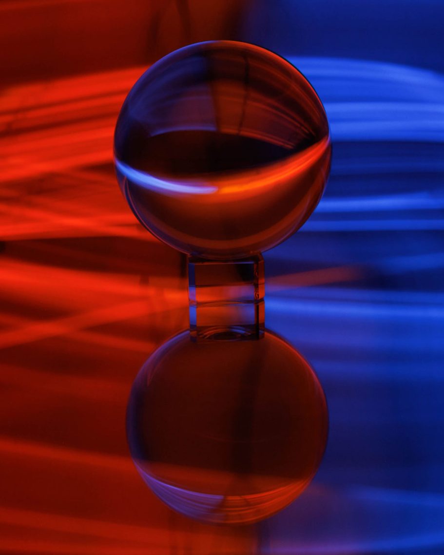Eine reflektierende Kugel vor einem verschwommenen roten und blauen Hintergrund.