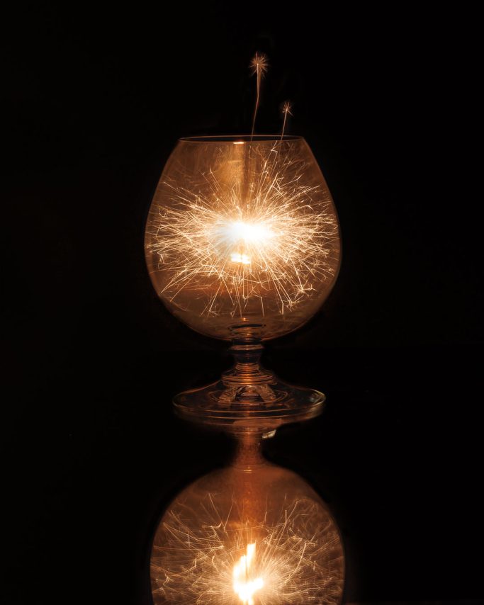 Glühende Funken in einer gläsernen Kugel mit reflektierendem Boden.