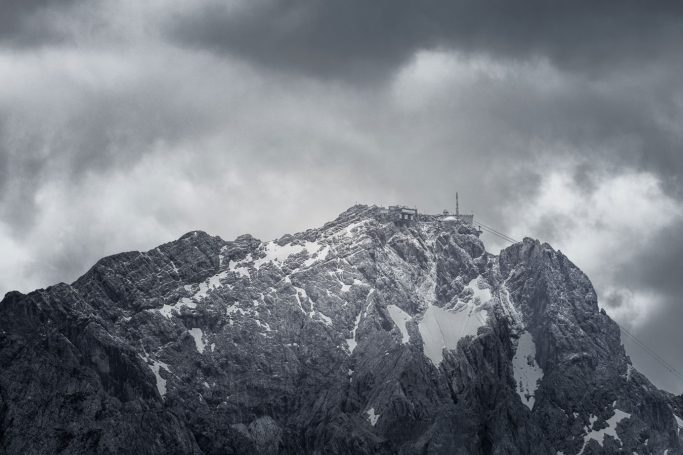 Schneebedeckter Berggipfel unter einem bewölkten Himmel in Schwarz-Weiß.