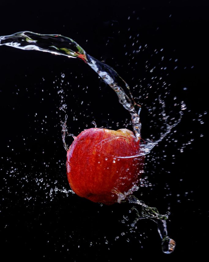 Rote Apfel wird von Wasser umgeben, das in einem Spritzverfahren sprudelt.