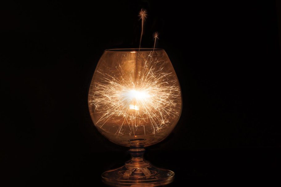Ein leuchtendes Glas mit Funken und sprühendem Licht bei dunklem Hintergrund.