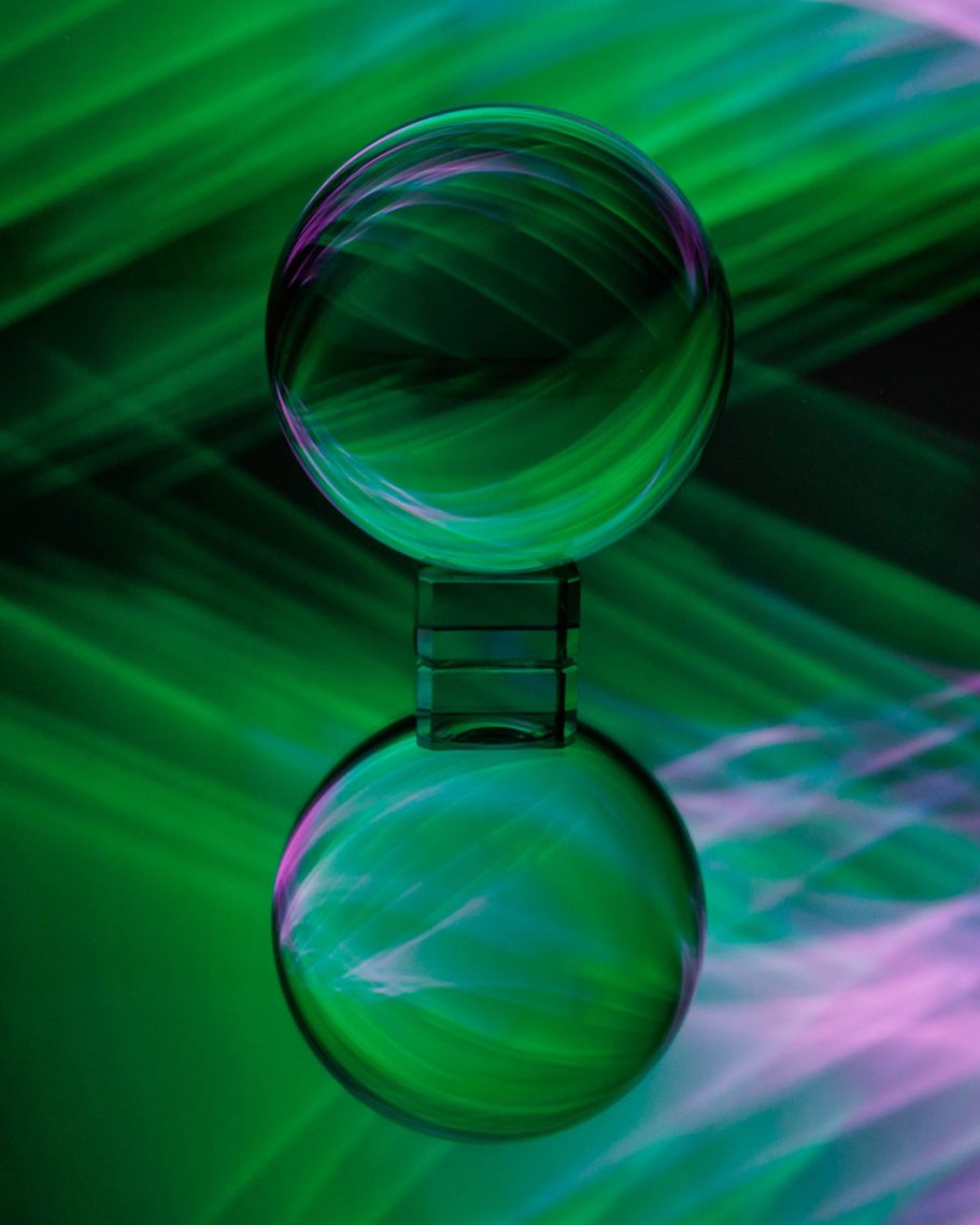 Zwei transparente Kugeln auf einem Hintergrund aus grünem und lila Lichtverlauf.