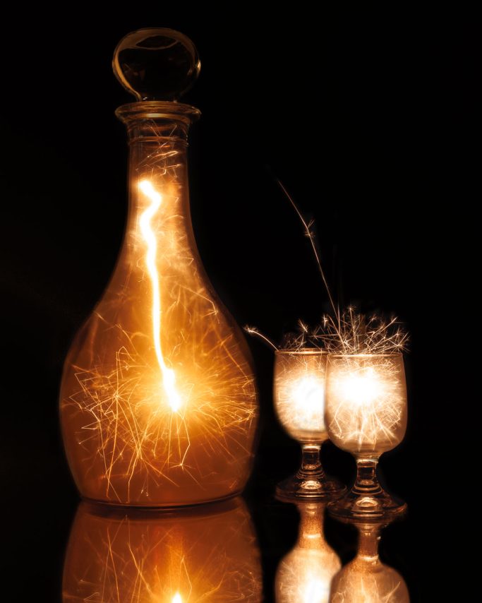 Glasbehälter und zwei Gläser mit funkelndem Licht auf schwarzem Hintergrund.